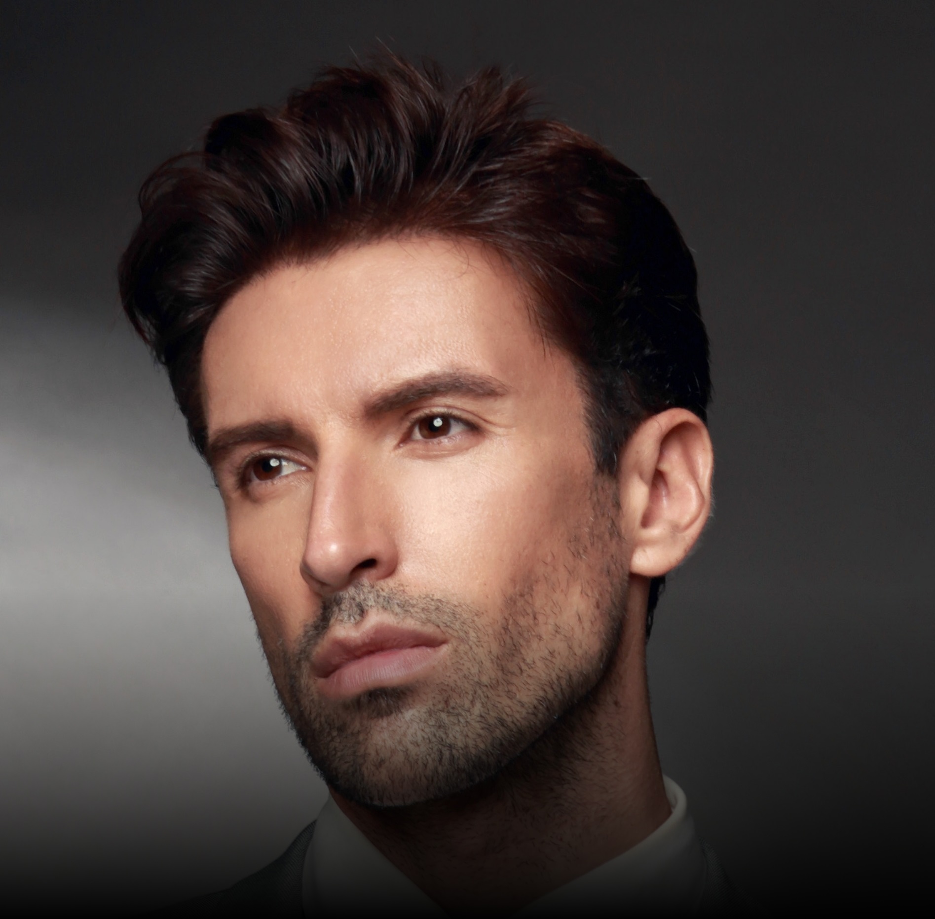 Portrait of a man with styled dark hair and stubble.