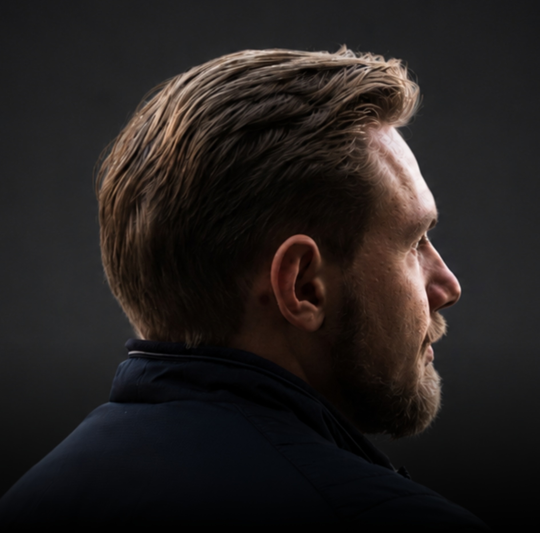 Side profile of a man with dramatic rim lighting.
