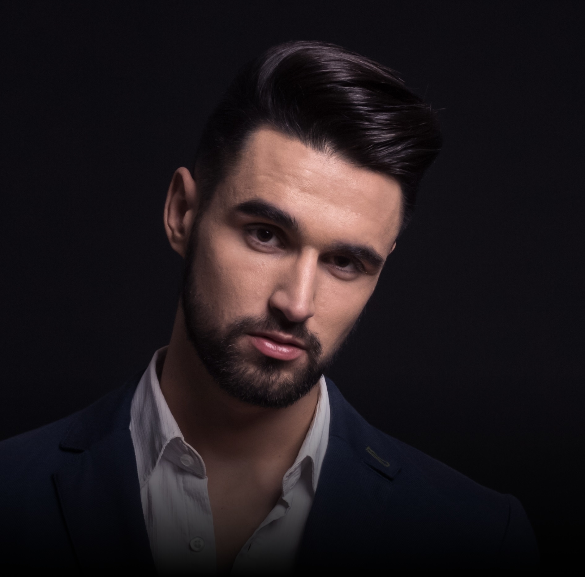 Portrait of a bearded man with a stylish pompadour hairstyle.