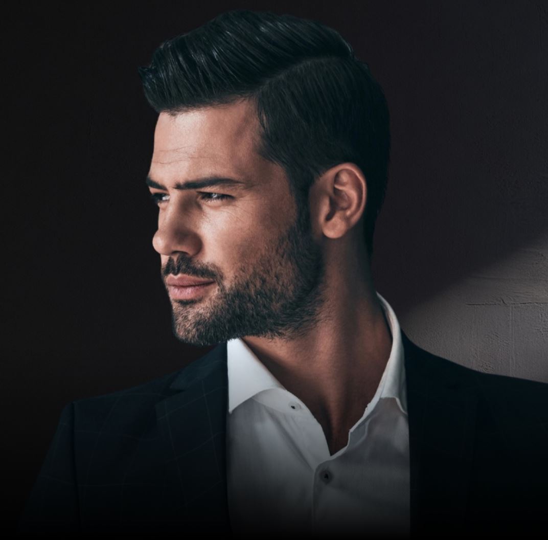 Portrait of a man in professional attire against dark background.